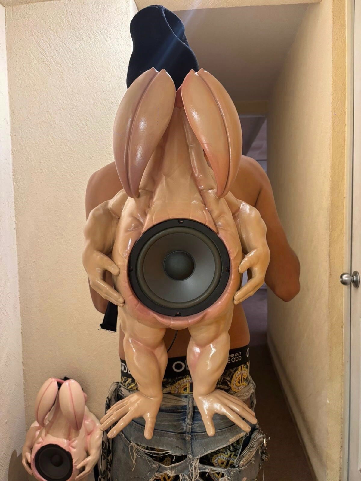 Ice Blade humanoid speaker backpack with long pale limbs and a large circular speaker embedded in its torso