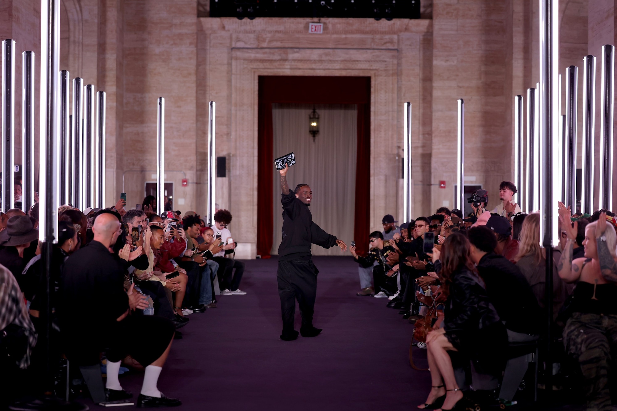A wide view of the VIVET Spring Summer 2027 runway with a figure standing between two rows of guests