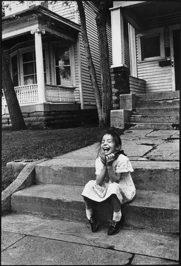Little girl laughing while sitting on a concrete s 1