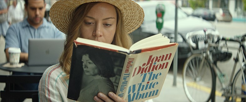 Ingrid (Aubrey Plaza) reads in a public place in I